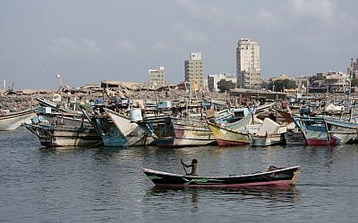 Un bateau de pêcheurs navigue devant le port d'Hodeida. En arrière-plan, des immeubles détruits par la coalition soutenue par l'Arabie saoudite et les Emirats arabes unis, le 28 septembre 2018 (Crédit : AP/Hani Mohammed)