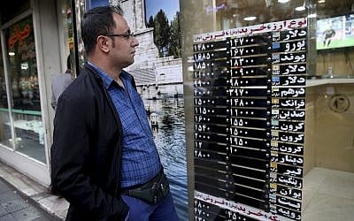Un Iranien regarde le taux de change à travers la vitrine d'une boutique du centre de Téhéran, en Iran, le 5 novembre 2018 (Crédit : AP/Ebrahim Noroozi)