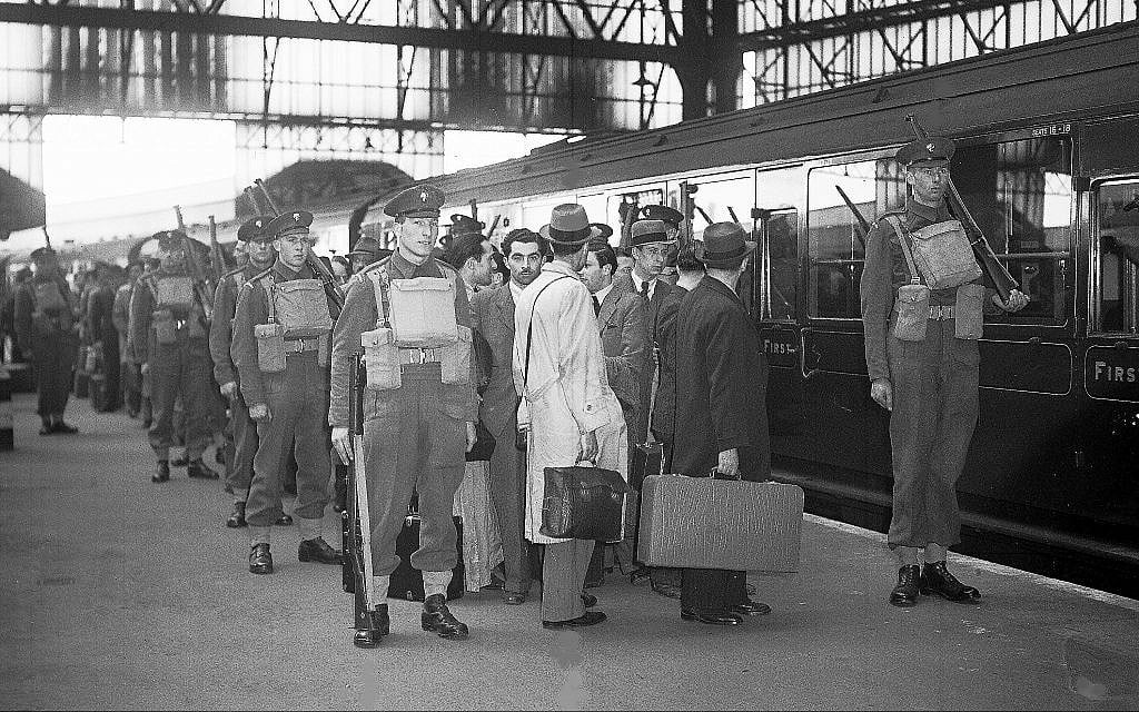 Des étrangers ennemis, arrêtés lors d'une grande rafle policière, quittent Londres, en Angleterre, le 17 mai 1940, sous une lourde escorte militaire pour des camps d'internement. (AP Photo)