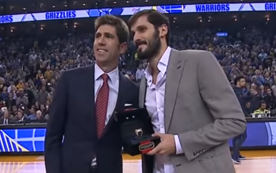 Le joueur de basket israélien Omri Casspi (à droite)reçoit la bague du champion de NBA de la part du directeur général Bob Myers à Oakland, avant le coup d'envoi du match opposant les Golden State Warriors aux Memphis Grizzlies, le 5 novembre 2018. (Crédit : capture d'écran YouTube)
