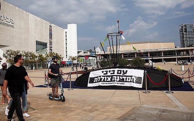 Des Israéliens regardent une structure ressemblant à un sous-marin avec une pancarte disant "Avec Bibi [Netanyahu], le pays est en train de couler", sur la place Habima de Tel Aviv, le 10 novembre 2018 (Crédit : Miriam Alster/Flash90)