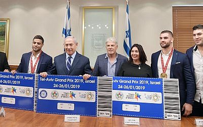 Le Premier ministre Benjamen Netanyahu et la ministre de la Culture et des Sports Miri Regev, entourés par l'équipe de judo israélienne présentent les futurs tickets pour le Grand Prix 2019 de Tel Aviv. (Crédit photo : GPO)