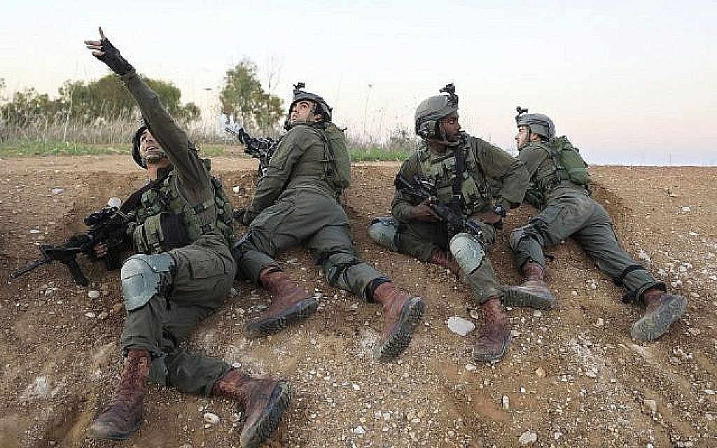 Des soldats israéliens se mettent à l'abri près de la frontière entre Israël et Gaza, le 12 novembre 2018. (Crédit : AP / Tsafrir Abayov)