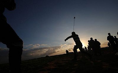 Un Palestinien utilise une fronde pour jeter des pierres pendant des émeutes près de la frontière avec Israël, à Khan Younès, dans le sud de la bande de Gaza, le 21 décembre 2018 (Crédit : Said Khatib/AFP)
