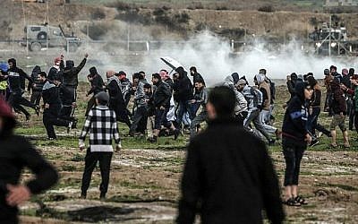 Des Palestiniens courent lors d'affrontements avec les forces israéliennes de l'autre côté de la barrière frontalière, à l'est de la ville de Gaza, le 28 décembre 2018. (Mahmud Hams/AFP)