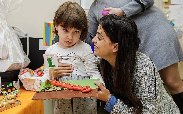 Liron Walter aide un enfant atteint de cancer à préparer une ménorah pour Hanoukka au jardin d'enfants "Daycare of Dreams" à Ramat Gan. (Avec l'aimable autorisation de Larger Than Life)