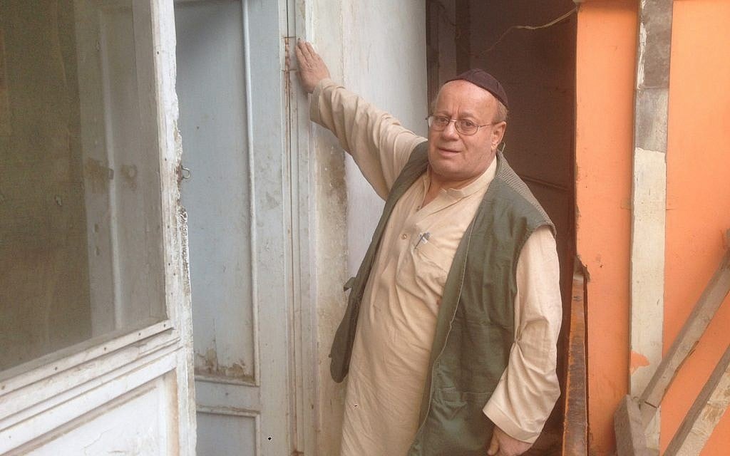 Zabolon Simantov touche la mézuzah accrochée à sa porte, un signe affirmé de vie juive  (Crédit : Ezzatullah Mehrdad/ Times of Israel)