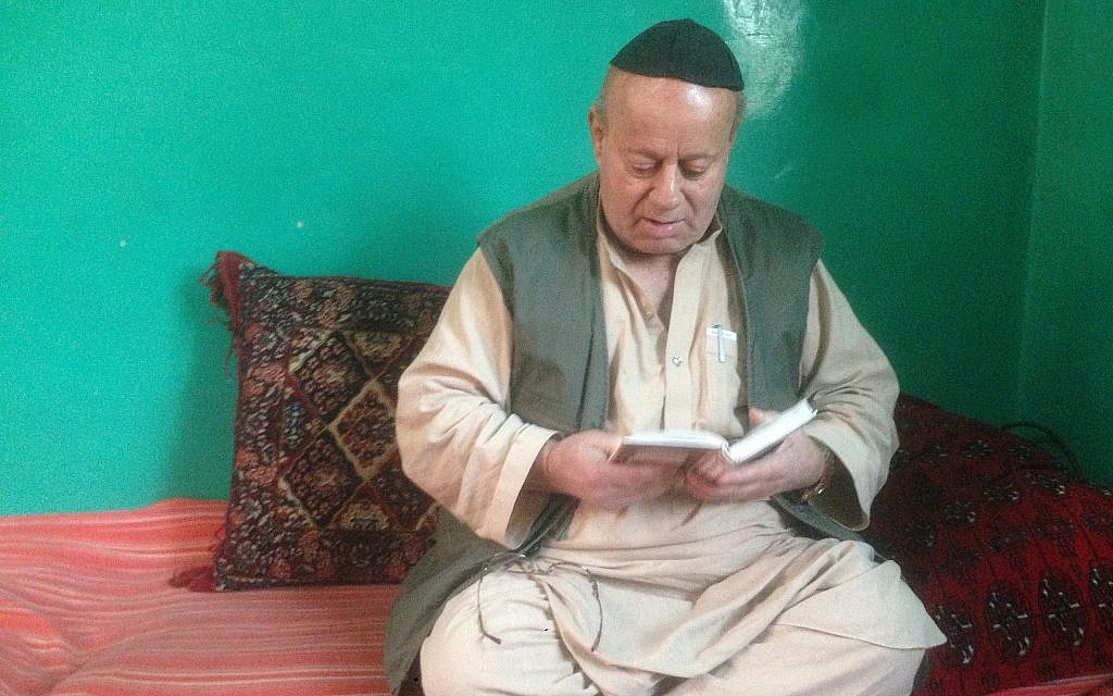 Zabolon Simantov récite la prière Shema écrite dans son livre de prières, à son domicile dans la dernière synagogue de Kaboul (Crédit :  Ezzatullah Mehrdad/ Times of Israel)