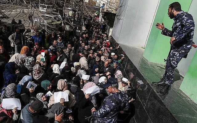 Les forces de sécurité fidèles au Hamas organisent une file d'attente devant le bureau de poste central de la ville de Gaza le 26 janvier 2019, alors que les Palestiniens se rassemblent pour recevoir une aide financière du Qatar. (Crédit : Mahmud Hams/AFP) Les forces de sécurité fidèles au Hamas organisent une file d'attente devant le bureau de poste central de la ville de Gaza le 26 janvier 2019, alors que les Palestiniens se rassemblent pour recevoir une aide financière du Qatar. (Crédit : Mahmud Hams/AFP)