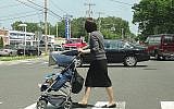 Une femme orthodoxe pousse une poussette à Lakewood (New Jersey) en 2013. La population de la ville orthodoxe en grande partie haredi a explosé au cours des deux dernières décennies, et les familles haredi cherchent à s'installer dans les villes voisines. (Dennis Fraevich/Flickr via JTA)