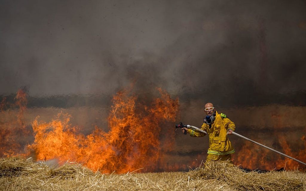 Des pompiers israéliens éteignent un incendie dans un champ de blé causé par des cerfs-volants incendiaires de manifestants palestiniens, près de la frontière avec la bande de Gaza, le 30 mai 2018. (Yonatan Sindel/Flash90)