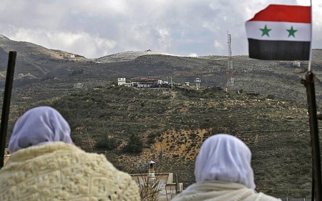 Des femmes druzes de Majdal Sham, sur le plateau du Golan, regardent de l'autre côté de la frontière, le 14 février 2019 (Crédit : JALAA MAREY / AFP)