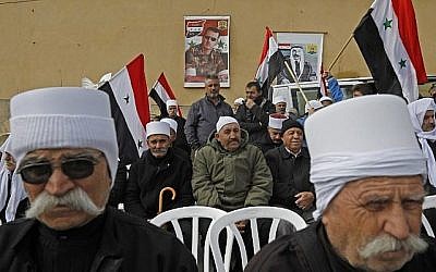 Les portraits du président Bashar al-Assad, au centre, et de feu le leader druze arabe Sultan al-Atrash, à droite, en arrière-plan pendant une manifestation à Madjal Shams, le 14 février 2019 (Crédit :JALAA MAREY / AFP)