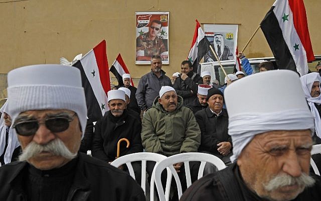 Les portraits du président Bashar al-Assad, au centre, et de feu le leader druze arabe Sultan al-Atrash, à droite, en arrière-plan pendant une manifestation à Madjal Shams, le 14 février 2019 (Crédit :JALAA MAREY / AFP)