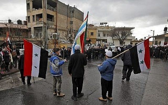 De jeunes résidents druzes sur le plateau du Golan brandissent les drapeaux syrien et druze durant un rassemblement dans le village de Majdal Shams sur le plateau du Golan, le 14 février 2019 (Crédit : JALAA MAREY / AFP)
