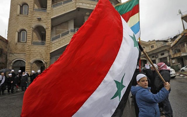 Un jeune résident druze du plateau du Golan brandit le drapeau national syrien durant un rassemblement dans le village de Majdal Shams, sur le plateau du Golan, le 14 février 2019 (Crédit :  JALAA MAREY / AFP)
