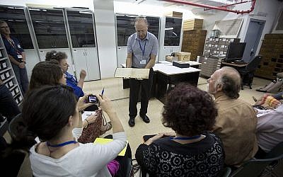 Le directeur des archives de Yad Vashem, Haim Gertner, montre un document à des experts internationaux en visite et à d'autres personnes qui participent à un atelier consacré à la préservation physique et numérique des documents, à Jérusalem, en septembre 2014. (AP Photo/Sebastian Scheiner)