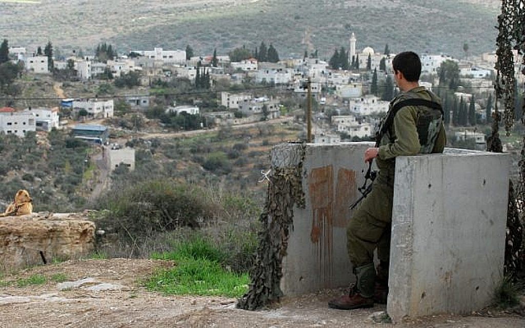 Photo d'illustration : Un soldat israélien garde l'implantation de Kedumim avec le village palestinien de Kadum en arrière-plan, le 13 novembre 2009 (Crédit : Gili Yaari/Flash90)