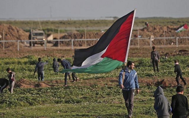 Un Palestinien porte le drapeau national lors d'une manifestation à proximité de la barrière de sécurité avec Israël à l'est de Gaza ville le 8 février 2019. (Photo de MAHMUD HAMS / AFP)