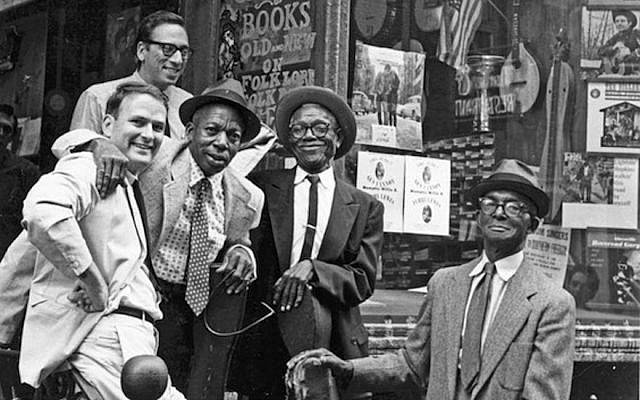 Izzy Young (au fond) au Folklore Center dans le quartier de Greenwich Village, New York, avec de gauche à droite : l'historien de la musique Sam Charters et les musiciens de blues Memphis Willie B., Furry Lewis, et Gus Cannon. (Crédit : Ann Charters via JTA) Izzy Young (au fond) au Folklore Center dans le quartier de Greenwich Village, New York, avec de gauche à droite : l'historien de la musique Sam Charters et les musiciens de blues Memphis Willie B., Furry Lewis, et Gus Cannon. (Crédit : Ann Charters via JTA)