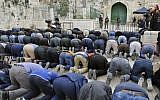 Des fidèles musulmans prient devant une barrière après que la police des frontières a fermé l'une des entrée du mont du Temple, dans la Vieille Ville de Jérusalem, le 12 mars 2019 (Crédit : Ahmad Gharabli/AFP)