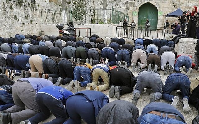 Des fidèles musulmans prient devant une barrière après que la police des frontières a fermé l'une des entrée du mont du Temple, dans la Vieille Ville de Jérusalem, le 12 mars 2019 (Crédit : Ahmad Gharabli/AFP)
