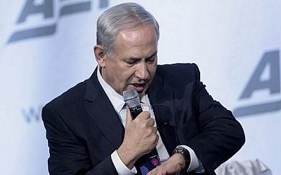 Le Premier ministre israélien Benjamin Netanyahu regarde sa montre en plaisantant dans un discours sur la paix au Moyen-Orient au National Building Museum, le 9 novembre 2015 à Washington, DC. (Crédit : AFP/Brendan SmialowskiI)