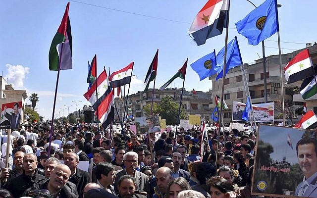 Des Syriens brandissent des portraits de Bashar el Assad durant une manifestation contre la reconnaissance de la souveraineté israélienne sur le plateau duGolan par Donald Trump, le 26 mars 2019. (Crédit : SANA via AP) Des Syriens brandissent des portraits de Bashar el Assad durant une manifestation contre la reconnaissance de la souveraineté israélienne sur le plateau duGolan par Donald Trump, le 26 mars 2019. (Crédit : SANA via AP)