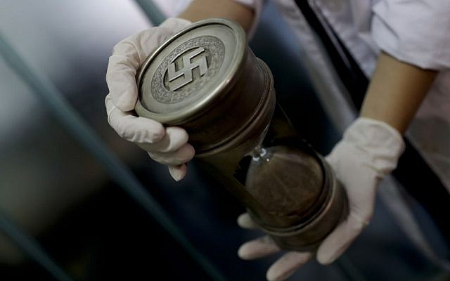 Illustration d'un policier fédéral tenant un sablier présentant des inscriptions nazies au siège d'Interpol à Buenos Aires, Argentine, le 16 juin 2017. (Crédit : AP/Natacha Pisarenko)