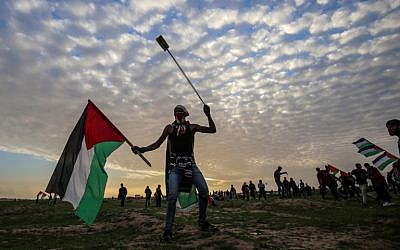A titre d'illustration : un manifestant palestinien porte un drapeau et une fronde lors d'une manifestation près de la clôture le long de la frontière avec Israël, à l'est de la ville de Gaza, le 1er février 2019. (Crédit : Saïd Khatib/AFP)