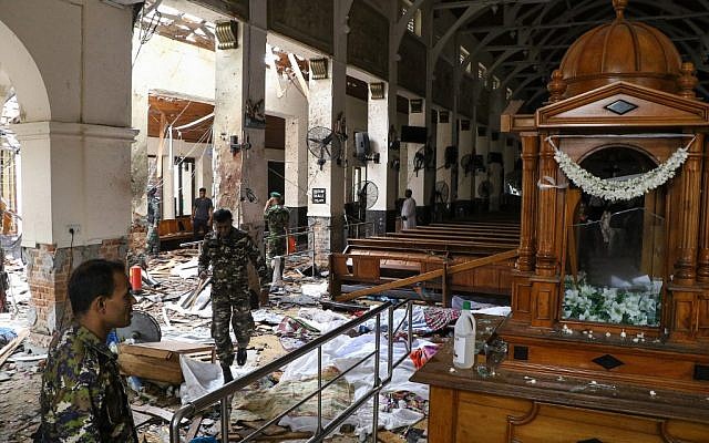 Les personnels de sécurité sri-lankais arpentent une église en évitant les dépouilles, au sol, des victimes qui ont été recouvertes de couvertures parmi les débris d'une explosion survenue au tombeau de Saint-Antoine, à Colombo, le 21 avril 2019 (Crédit :  ISHARA S.  KODIKARA / AFP)