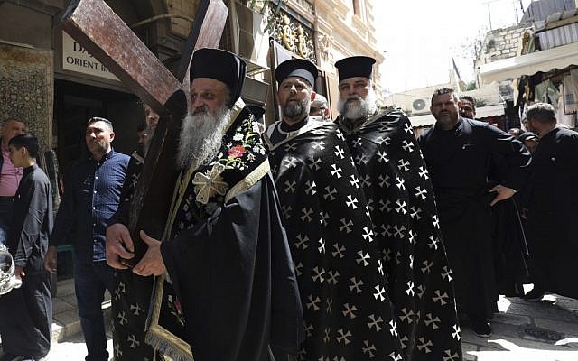 Un évêque grec-orthodoxe porte une croix de bois lors de la procession Via Dolorosa du vendredi saint dans la Vieille ville de Jérusalem, le 26 avril 2019 (Crédit : GALI TIBBON / AFP)
