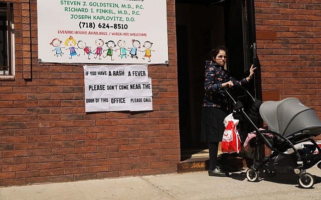 Un panneau mettant en garde contre les symptômes de la rougeole dans le quartier ultra-orthodoxe de Williamsburg, à New York, le 10 avril 2019. (Crédit : Spencer Platt/Getty Images/AFP) Un panneau mettant en garde contre les symptômes de la rougeole dans le quartier ultra-orthodoxe de Williamsburg, à New York, le 10 avril 2019. (Crédit : Spencer Platt/Getty Images/AFP)