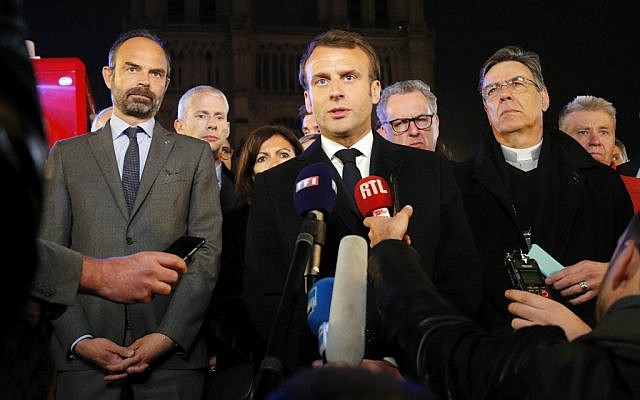 Le président Emmanuel Macron, accompagné de la maire de Paris Anne Hidalgo, du Premier ministre Edouard Philippe, du ministre de la Culture Franck Riester et de l'évêque de Paris Michel Aupetit, lors de son intervention à proximité de la cathédrale Notre-Dame de Paris, en proie aux flammes, le 15 avril 2019. (Crédit photo : PHILIPPE WOJAZER / POOL / AFP)