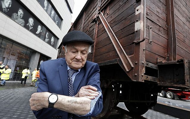 Le survivant de la Shoah Leon Kaner, 94 ans, montre son numéro de tatouage devant un wagon plombé allemand similaires à ceux utilisés pour transporter les déportés vers Auschwitz et vers les différents camps de la mort, aux abords du musée du patrimoine juif de New York, le 31 mars 2019. (Crédit : AP Photo/Richard Drew) Le survivant de la Shoah Leon Kaner, 94 ans, montre son numéro de tatouage devant un wagon plombé allemand similaires à ceux utilisés pour transporter les déportés vers Auschwitz et vers les différents camps de la mort, aux abords du musée du patrimoine juif de New York, le 31 mars 2019. (Crédit : AP Photo/Richard Drew)