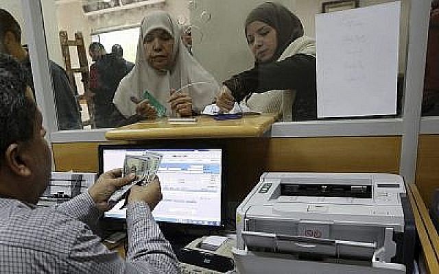Une employée du gouvernement nommée par le Hamas à Gaza signe un document pour obtenir 50 % de son salaire qui aurait dû être versé depuis longtemps sur des fonds donnés par le Qatar, tandis que d'autres attendent dans la queue, au bureau de poste principal de Gaza, à Gaza City, le 7 décembre 2018. (AP Photo/Adel Hana) Une employée du gouvernement nommée par le Hamas à Gaza signe un document pour obtenir 50 % de son salaire qui aurait dû être versé depuis longtemps sur des fonds donnés par le Qatar, tandis que d'autres attendent dans la queue, au bureau de poste principal de Gaza, à Gaza City, le 7 décembre 2018. (AP Photo/Adel Hana)