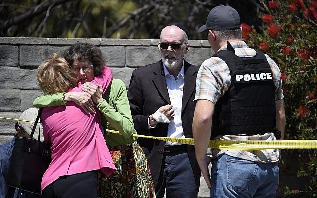 Deux personnes se réconfortent mutuellement aux abords de la synagogue Habad de Poway, en Californie, après une fusillade, le 27 avril 2019 (Crédit : AP/Denis Poroy)