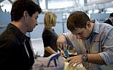 Les personnels de sécurité contrôlent les bagages d'un passager à l'aéroport Ben-Gurion. Photo d'illustration (Crédit : AP/Ariel Schalit)