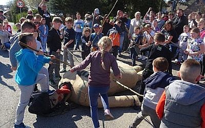 Des enfants en train de frapper avec des bâtons dune marionnette de Judas pour le Vendredi Saint, dans la ville de Pruchnik, en Pologne, le 19 avril 2019. (Crédit : Hubert Lewkowicz/AFP)