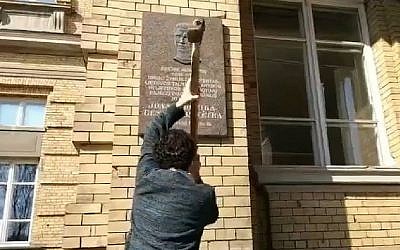 Stanislovas Tomas tente de détruire la plaque en l'honneur de Jonas Noreika à Vilnius,Lituanie,le 7 avril 2019. (Crédit : capture écran/Facebook)