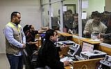 Des employés aident les Palestiniens à recevoir l'aide financière apportée par le Qatar aux familles défavorisées au bureau central de poste de Gaza City, le 26 janvier 2019 (Crédit : Mahmud Hams/AFP)