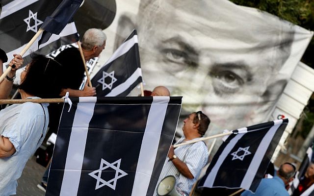 Les Israéliens brandissent des drapeaux lors d'un rassemblement contre le Premier ministre Benjamin Netanyahu à Tel Aviv, le 25 mai 2019 (Crédit : JACK GUEZ / AFP)