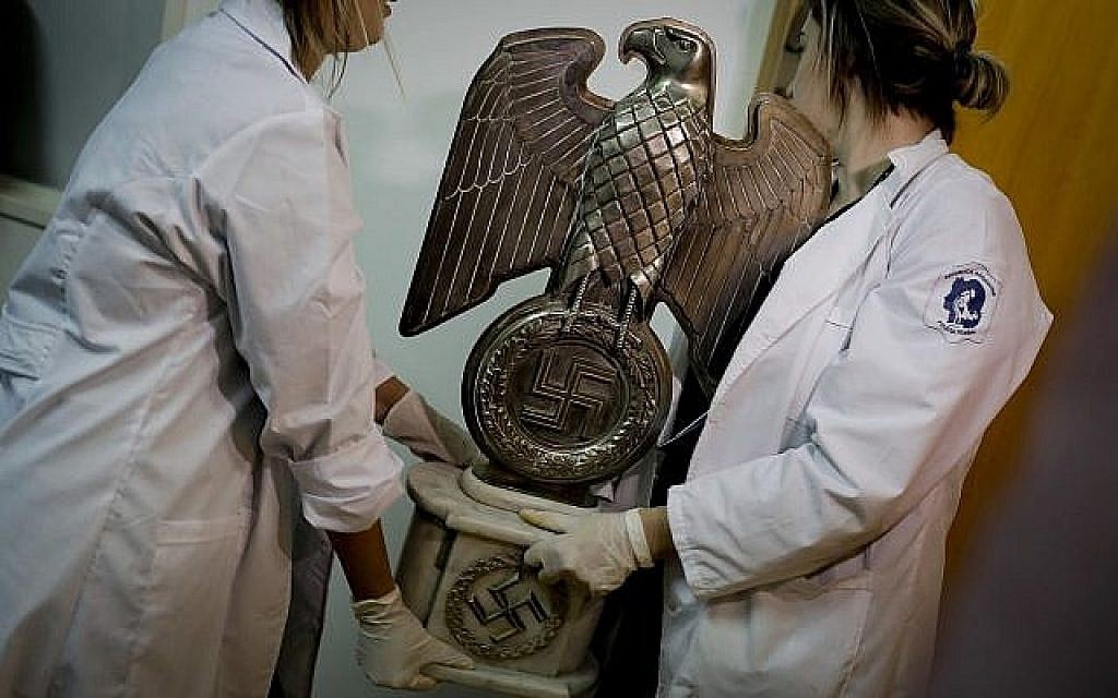 A titre d'illustration : Des membres de la police fédérale portent une statue nazie au siège d'Interpol à Buenos Aires, en Argentine, le vendredi 16 juin 2017. Dans une pièce cachée d'une maison près de la capitale argentine, la police a découvert le 8 juin la plus grande collection d'objets nazis de l'histoire du pays. Les autorités disent qu'elles soupçonnent qu'il s'agit d'originaux ayant appartenu à des nazis de haut rang en Allemagne pendant la Seconde Guerre mondiale. (AP Photo/Natacha Pisarenko) A titre d'illustration : Des membres de la police fédérale portent une statue nazie au siège d'Interpol à Buenos Aires, en Argentine, le vendredi 16 juin 2017. Dans une pièce cachée d'une maison près de la capitale argentine, la police a découvert le 8 juin la plus grande collection d'objets nazis de l'histoire du pays. Les autorités disent qu'elles soupçonnent qu'il s'agit d'originaux ayant appartenu à des nazis de haut rang en Allemagne pendant la Seconde Guerre mondiale. (AP Photo/Natacha Pisarenko)