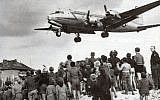 Des habitants de Berlin Ouest observent l’atterrissage d’un Rosinenbomber à Tempelhof, en 1948. (Domaine public)
