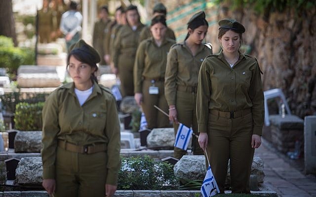 Des soldates placent des drapeaux israéliens sur les tombes de soldats au cimetière militaire du mont Herzl, à Jérusalem, le 16 avril 2018, avant Yom HaZikaron, le Jour du souvenir des soldats israéliens tombés au combat. (Hadas Parush/Flash90) Des soldates placent des drapeaux israéliens sur les tombes de soldats au cimetière militaire du mont Herzl, à Jérusalem, le 16 avril 2018, avant Yom HaZikaron, le Jour du souvenir des soldats israéliens tombés au combat. (Hadas Parush/Flash90)