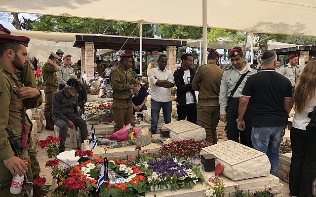 Les membres d'une famille en deuil devant la tombe de leur proche disparu au cimetière militaire d'Ashkelon à Yom HaZikaron, le 8 mai 2019 (Crédit : Jacob Magid/Times of Israel)