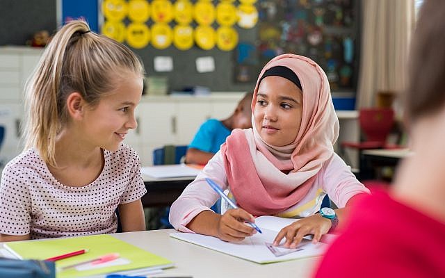 Illustration : une écolière vêtue d'un hijab à côté d'une camarade de classe. (Crédit : Ridofranz via iStock) Illustration : une écolière vêtue d'un hijab à côté d'une camarade de classe. (Crédit : Ridofranz via iStock)