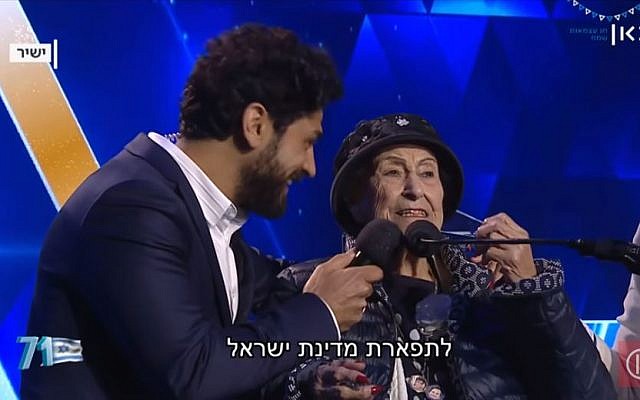 Aviv Alush, (à gauche), qui a animé la cérémonie, et Marie Nahmias, 93 ans, qui a allumé une torche lors de Yom HaAstmaout, à Jérusalem, le 8 mai 2019. (Capture d'écran : Kan) Aviv Alush, (à gauche), qui a animé la cérémonie, et Marie Nahmias, 93 ans, qui a allumé une torche lors de Yom HaAstmaout, à Jérusalem, le 8 mai 2019. (Capture d'écran : Kan)