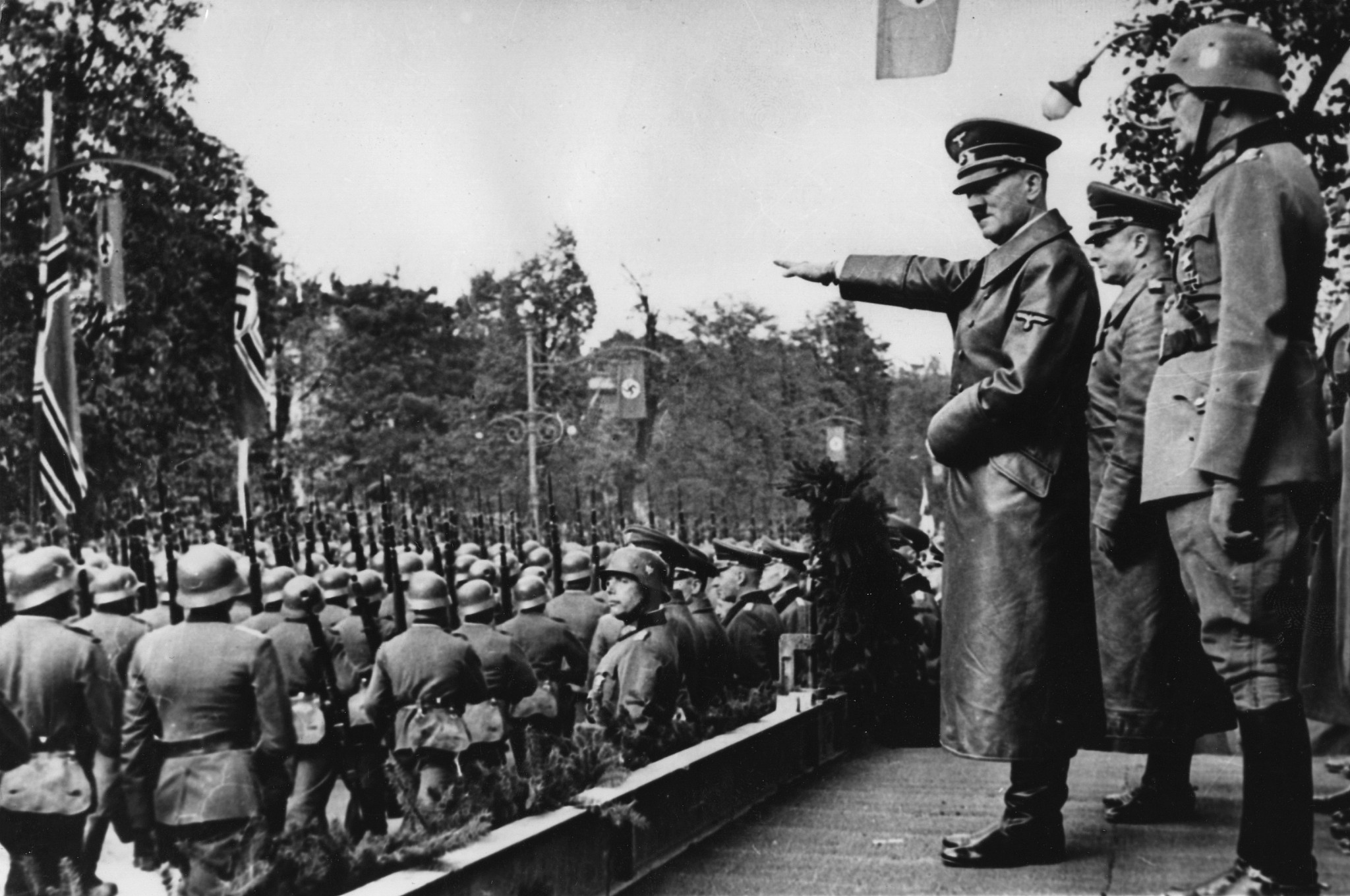 Adolf Hitler, (au centre), saluant les troupes de la Wehrmacht allemande qui défilent à Varsovie, en Pologne, au mois d'octobre 1939, après l'invasion allemande. Derrière, de gauche à droite : Le commandant en chef de l'armée, le  Colonel Général Walther von Brauchitsch, le nouveau commandant de Varsovie, le Lieutenant Général Friedrich von Cochenhausen, le Colonel Général Gerd von Rundstedt, le Colonel Général Wilhelm Keitel. (Crédit : AP Photo)