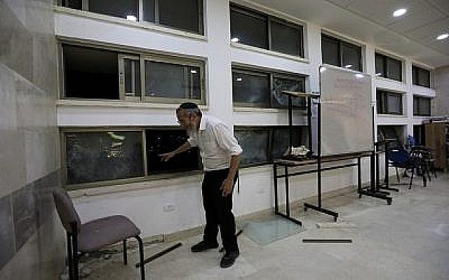 Un rabbin à l'intérieur d'une école religieuse de Sderot, en Israël, après qu'elle a été touchée par une roquette tirée depuis la bande de Gaza, le 13 juin 2019. (Crédit : AP/Tsafrir Abayov)